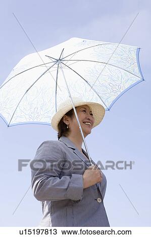 Stock Image - Senior woman holding parasol. Fotosearch
