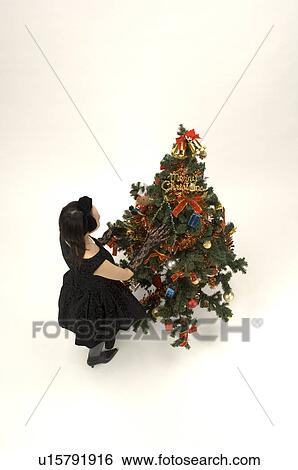Stock Photograph - Young woman decorating Christmas tree. Fotosearch