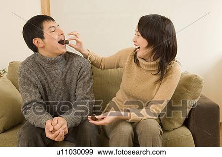 Stock Photo - Young woman feeding young man chocolate. Fotosearch