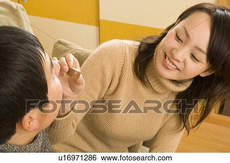 Stock Photograph - Young woman feeding young man chocolate. Fotosearch