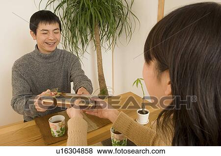 Stock Photo - Young woman giving Valentine's Day gift to young man. Fotosearch