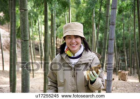 Stock Photography - Young woman holding bamboo shoot. Fotosearch