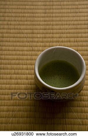 Stock Image - A cup of Japanese tea on a Tatami mat, high angle view, close up, Japan. Fotosearch