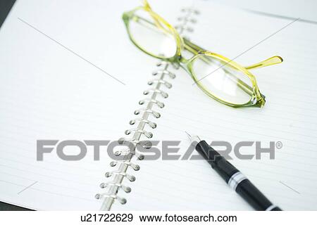 Stock Photo - Full Frame Shot Of a Pen And a Glass On Notebook, High Angle View. Fotosearch