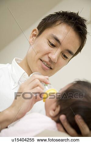 Stock Photography - Baby drinking milk with dad. Fotosearch