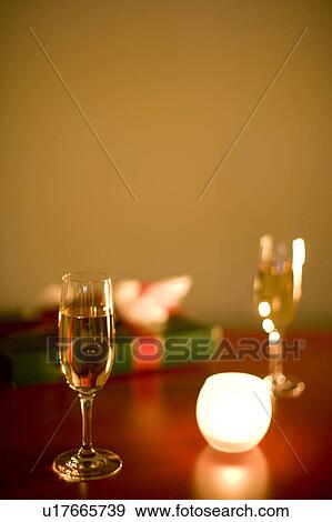 Stock Photo - Champagne glasses on table with candle and present. Fotosearch