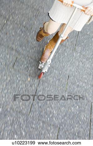 Stock Photo - Feet of woman riding a kick scooter. Fotosearch