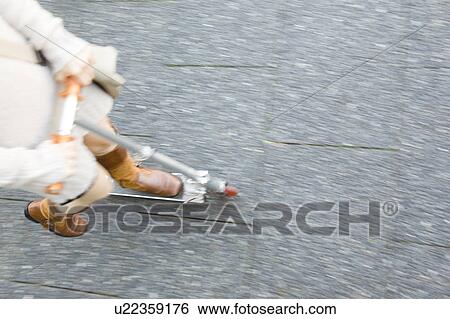 Feet of woman riding a kick scooter View Large Photo Image Stock Photograph - Feet of woman riding a kick scooter. Fotosearch