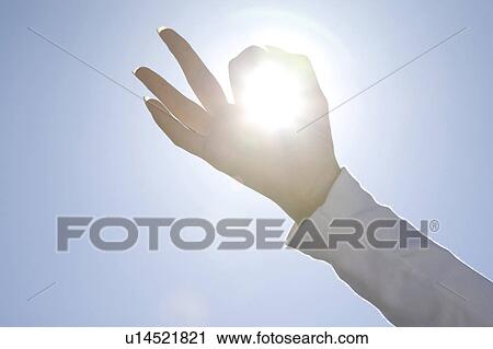 Stock Image - Finger encircling the sun. Fotosearch