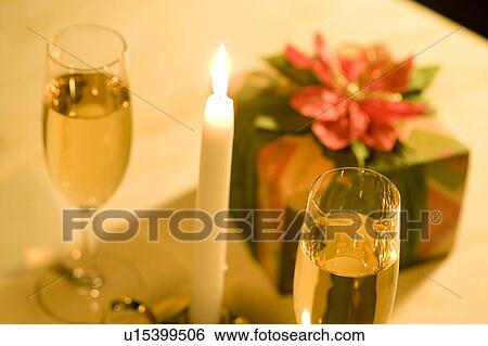 Gift on table with champagne glasses and burning candle View Large Photo Image Stock Photograph - Gift on table with champagne glasses and burning candle. Fotosearch