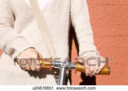 Stock Image - Hand of a woman grasping the handle of the kick scooter. Fotosearch