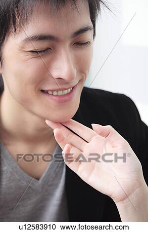 Stock Image - Hand touching boyfriend's chin. Fotosearch