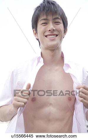 Stock Photography - Portrait of young man putting on shirt. Fotosearch
