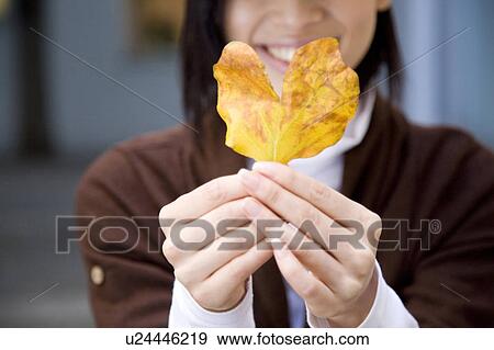 Portrait of young woman holding a leaf View Large Photo Image Stock Photo - Portrait of young woman holding a leaf. Fotosearch