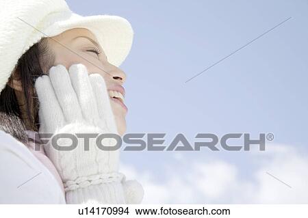 Picture - Portrait of young woman with hat and glove to her face. Fotosearch
