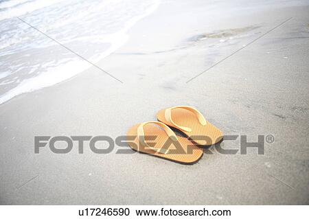 Stock Image - Sandals left on sandy beach. Fotosearch