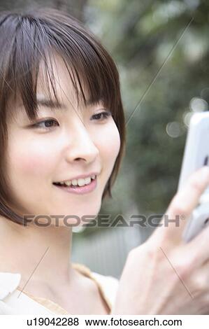Stock Photo - Smiling woman looking at cell phone. Fotosearch