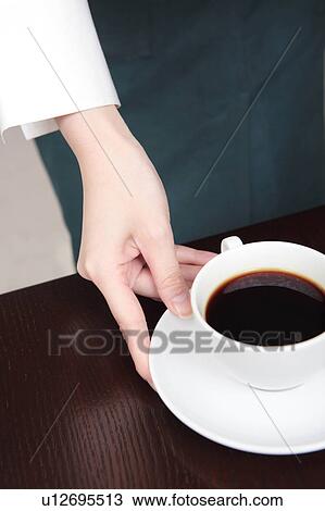 Stock Image - Waitress serving a cup of coffee. Fotosearch