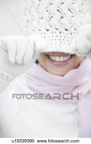 Stock Image - Woman covering the face with a knit hat. Fotosearch
