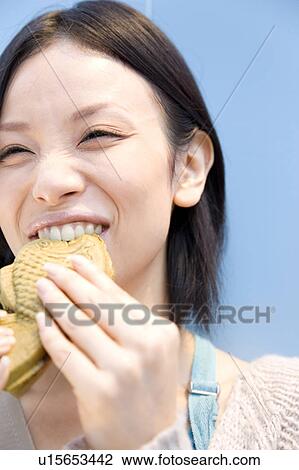 Stock Image - Woman eating a Taiyaki. Fotosearch