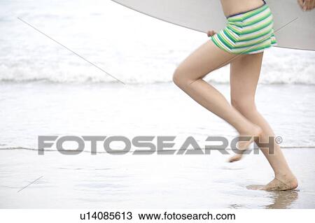 Stock Image - Woman in swimsuit holding a surfboard . Fotosearch