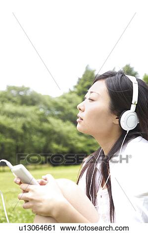 Woman listening to music in a park View Large Photo Image Stock Image - Woman listening to music in a park. Fotosearch