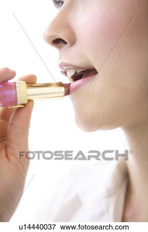 Stock Photo - Woman putting on lipstick. Fotosearch