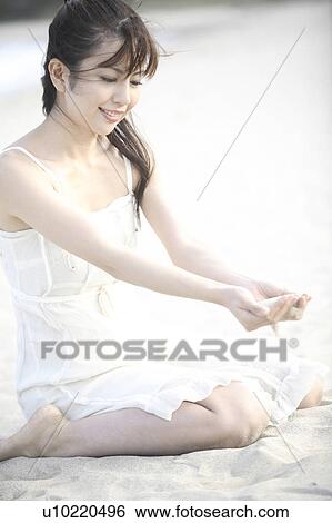 Stock Photograph - Woman scooping the sand on the beach. Fotosearch