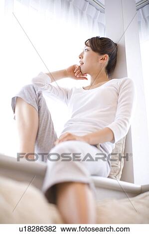 Stock Image - Woman sitting near the window. Fotosearch