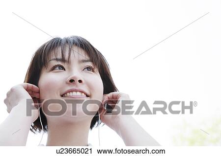 Stock Image - Woman smiling and listening to music. Fotosearch