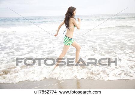 Woman walking on a beach in swimsuit View Large Photo Image Picture - Woman walking on a beach in swimsuit. Fotosearch