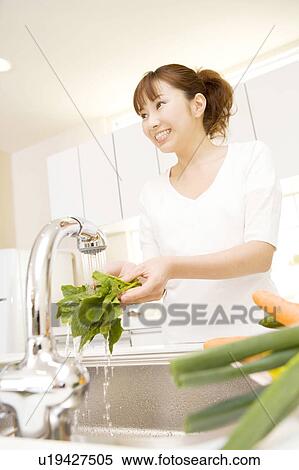 Stock Photography - Woman washing vegetables. Fotosearch