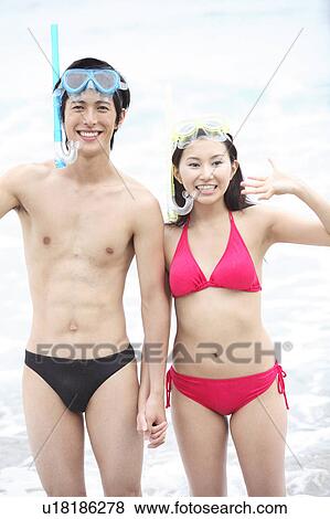 Stock Photo - Young couple in swimsuits at the beach. Fotosearch