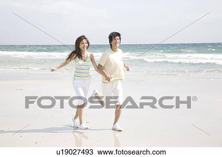 Young couple running on a beach View Large Photo Image Stock Image - Young couple running on a beach. Fotosearch