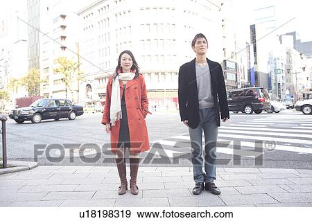 Stock Photo - Young man and woman standing on the sidewalk. Fotosearch