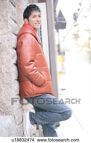 Young man leaning against a wall View Large Photo Image Picture - Young man leaning against a wall. Fotosearch