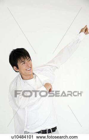 Stock Image - Young man putting on a shirt. Fotosearch