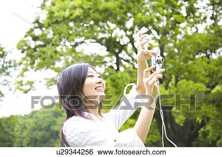 Stock Photograph - Young woman shooting a photo. Fotosearch