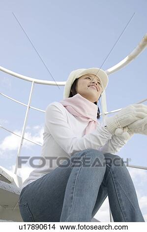 Young woman sitting down below the blue sky View Large Photo Image Picture - Young woman sitting down below the blue sky. Fotosearch