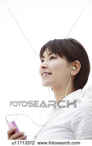 Young woman smiling and listening to music View Large Photo Image Stock Image - Young woman smiling and listening to music. Fotosearch