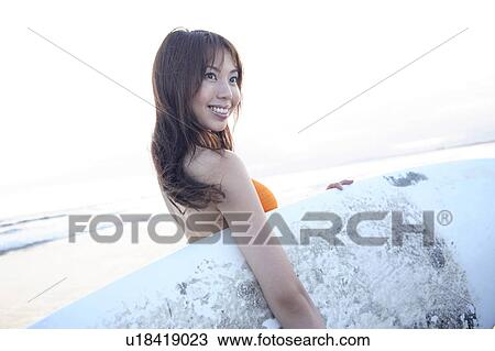 Stock Image - Young woman surfer at Enoshima beach. Fotosearch