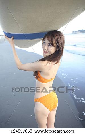 Stock Image - Young woman surfer in Enoshima beach. Fotosearch