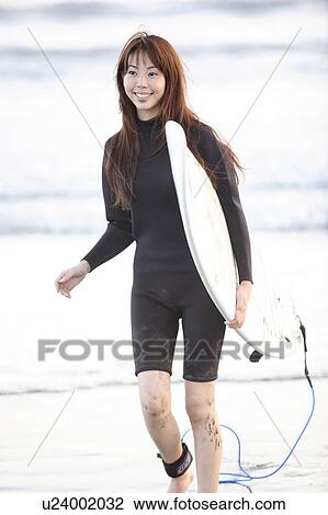 Stock Image - Young woman surfing at Enoshima beach. Fotosearch