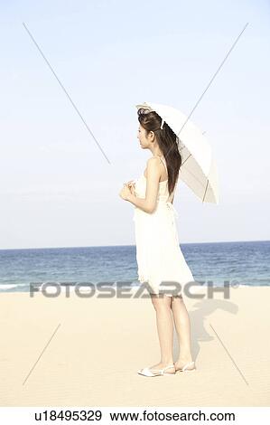 Stock Photo - Young woman with umbrella on the beach. Fotosearch