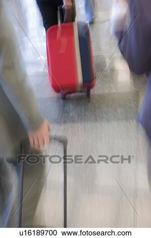 Stock Image - Blurred view of business executives pulling their luggage. Fotosearch