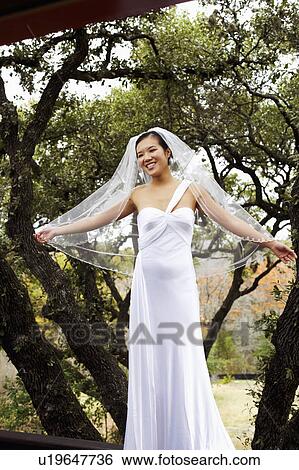 Stock Photograph - Bride standing with her arms outstretched and smiling. Fotosearch