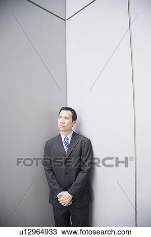 Stock Image - Businessman standing in a corner with his hands clasped. Fotosearch