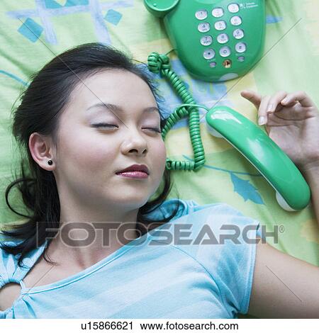 Stock Image - Close-up of a young woman sleeping with a telephone beside her. Fotosearch