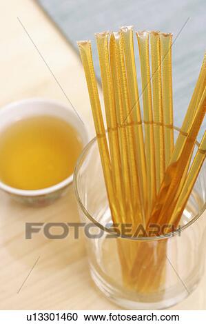 Stock Image - Close-up of honey sachets in a glass with a bowl of aromatherapy oil on the table. Fotosearch