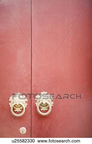 Stock Image - Close-up of two doorknockers with a keyhole on a door. Fotosearch